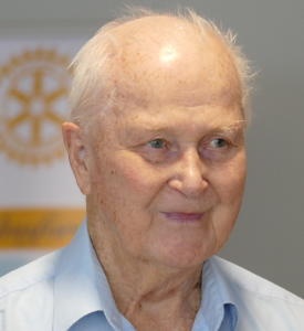 Head and shoulders of an elderly man wearing an open-neck blue shirt