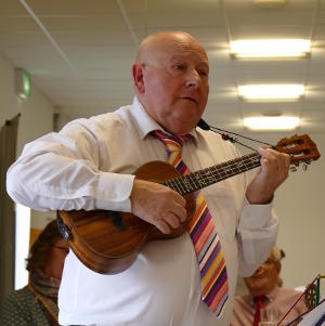 A bald man playing a ukulele