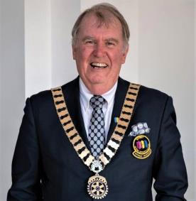 A smiling man wearing a chain of office