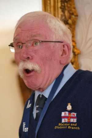 A smiling white-haired man wearing glasses