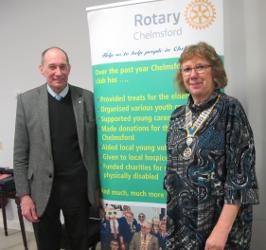 A man and a woman standing either side of a Rotary banner