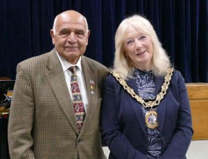 A bald man wearing a sports jacket standing next to a blonde woman wearing a mayor's chain