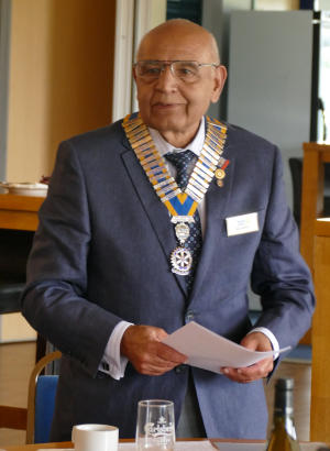 A smiling bald man wearing a chain of office