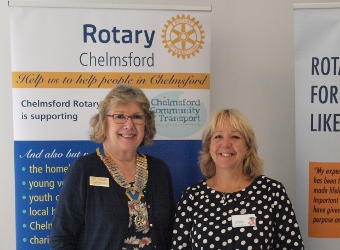 Two ladies standing in front of Rotary banners