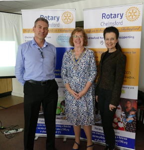 A man and two women standing in front of two Rotary banners