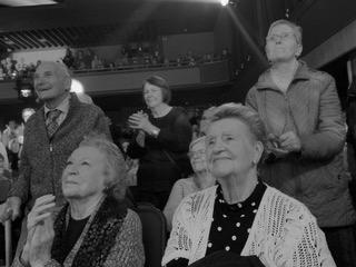 Black and white photo of senior citizens enthusiastic about a theatrical performance