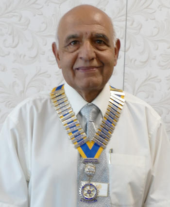 A smiling bald man wearing a chain of office