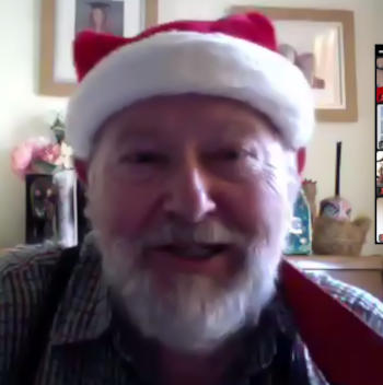 A smiling bearded man in a Santa hat