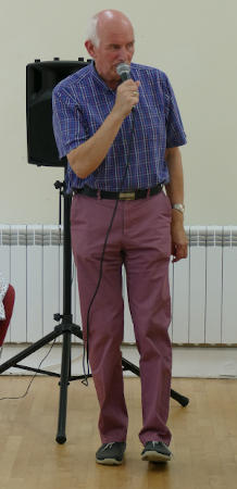 A man in shirtsleeves using a microphone