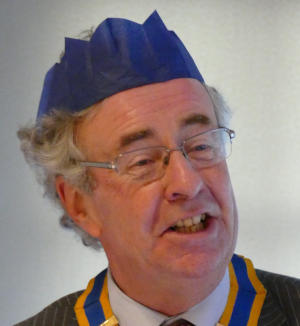Head of a smiling man wearing a paper hat from a Christmas cracker