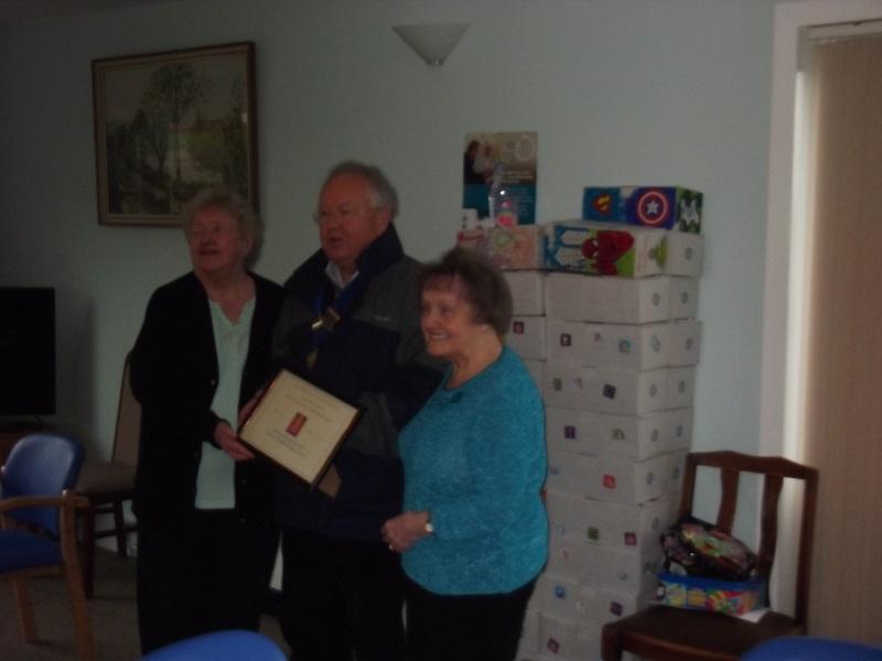 2014 Shoebox Project - Rotarian John Paul presents a certificate to members of the Monkton Place community in recognition of their donations to the Rotary Shoebox Project 