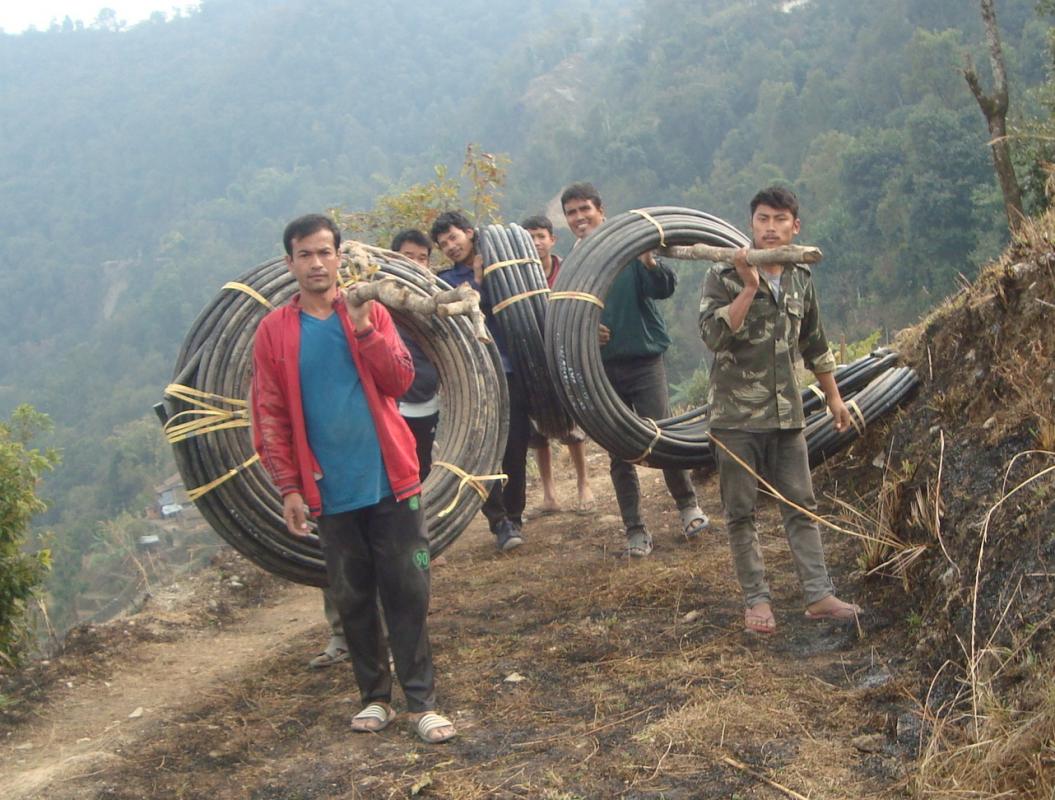 Nepal Water Project Completion Report - Locals transport pipe coils to the water source from the nearest road head