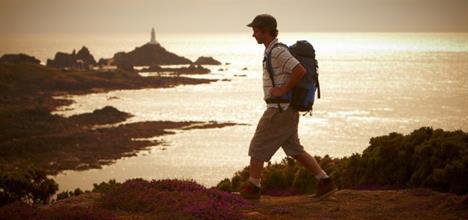 Island Walk Sponsored by TMF Group - A walker silhouetted as he walks past Cobiere Lighthouse