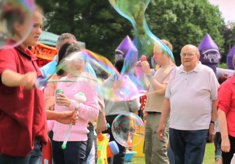 About Our Club - Summer Fair attendees, seen through a cloud of bubbles!